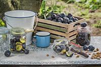 Fresh and preserved plums in glass jars on a garde