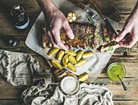 Man eating roasted pork ribs with garlic, rosemary