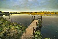 Silent pond surface in sunset time. Tranquil lands